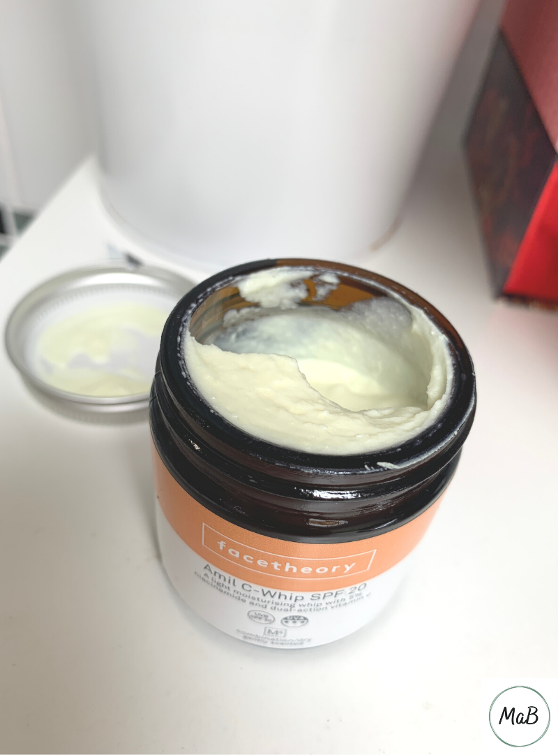 A photo pf a jar of Facetheory Amil C-Whip cream with the lid off. The moisturiser inside has a cream, whipped texture.